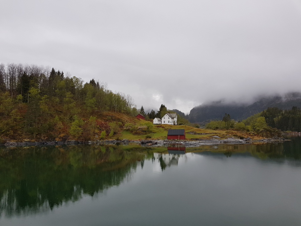 Low clouds hanging over the fjords, creating a mystical and serene landscape, with mountains partially hidden in mist.