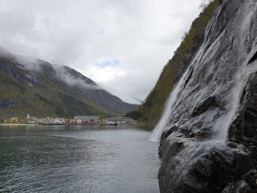 Waterfall cascading down a cliff along the fjords, viewed up close from a cruise boat departing from Bergen.